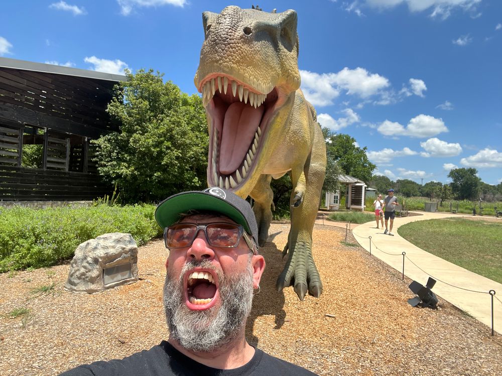 A man standing in front of a raging tyranosaurus rex