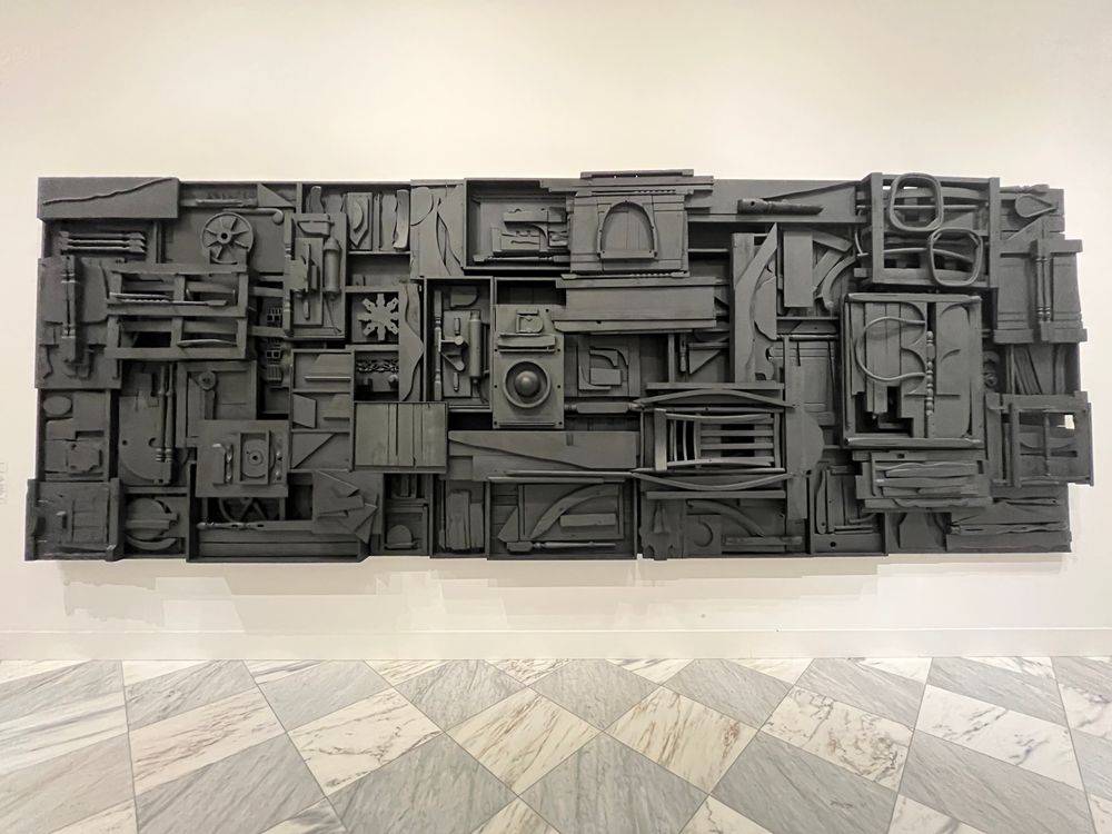 A large black collage of wooden shapes