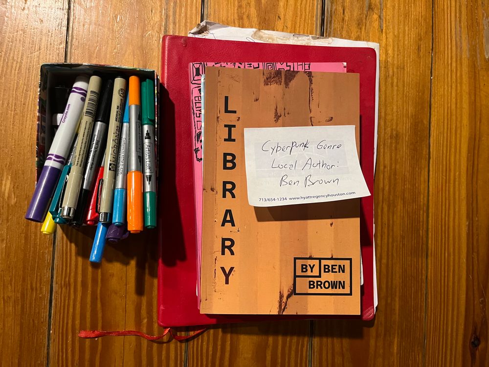 A copy of my book LIBRARY sitting on the bar at a coffee shop next to some pens