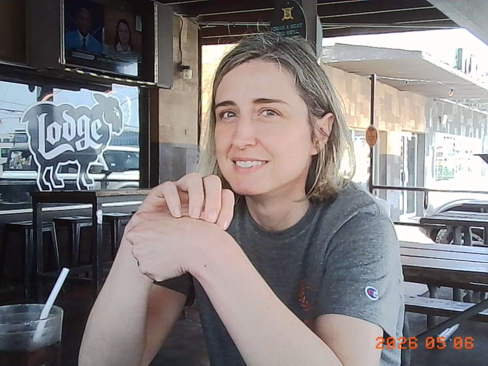 A nice looking lady sitting at an outdoor table.